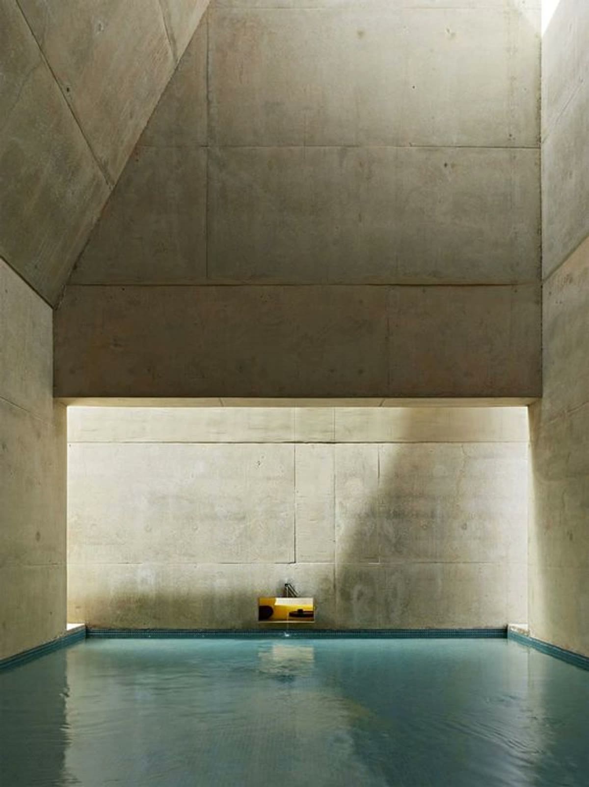 A quiet indoor stone pool with still water and a skylight